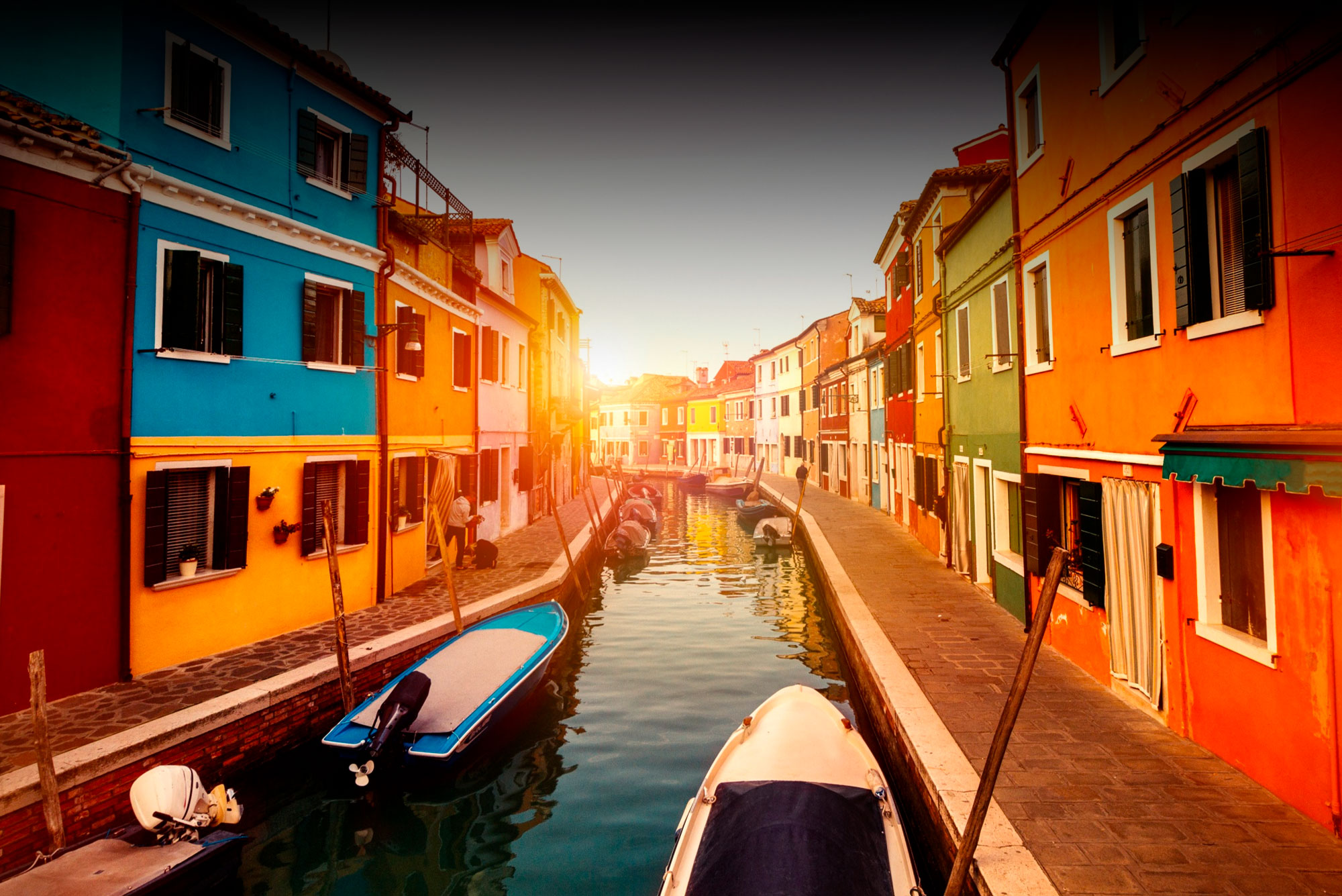 beautiful-sunset-with-boats-buildings-and-water-sun-light-toning-burano-italy-min